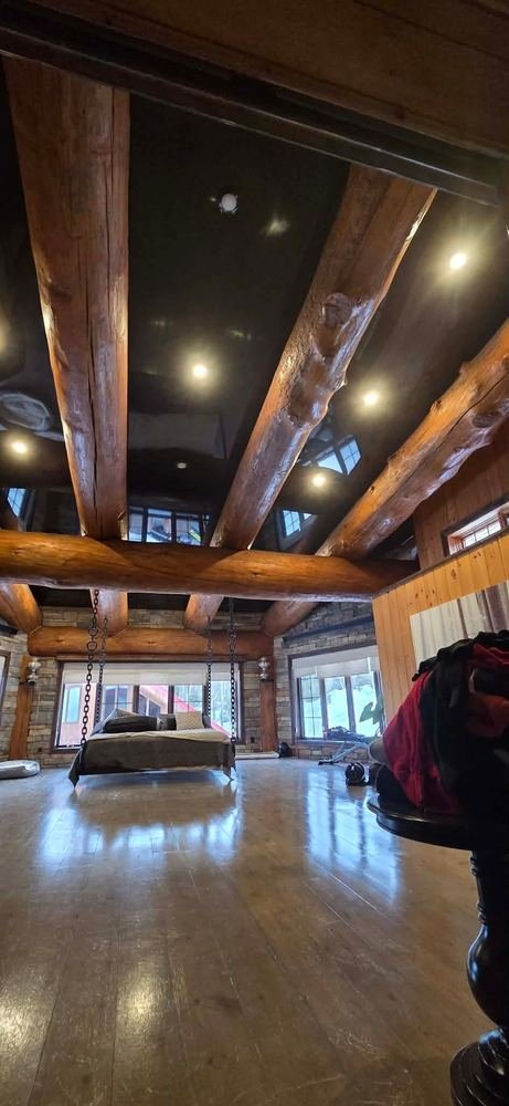 Plafond tendu Extenzo noir — grande salle avec poutres